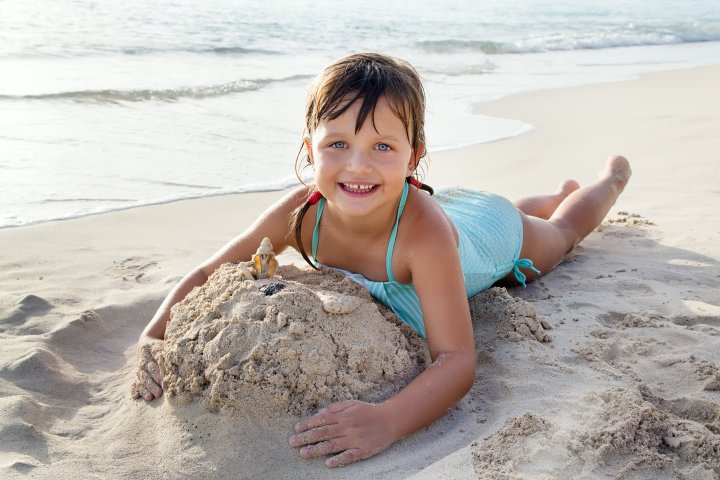 a young boy sitting on top of a sandy beach