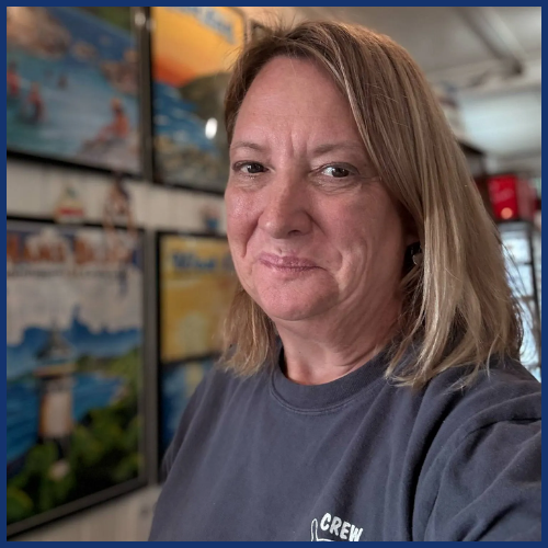 Smiling woman with shoulder-length hair in front of wall art.