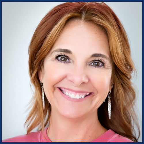 Smiling woman with earrings, brown hair, wearing a pink top.